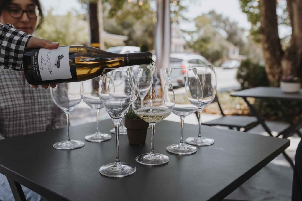 a bottle of sojourn cellars wine being poured on the patio of their sonoma square tasting room