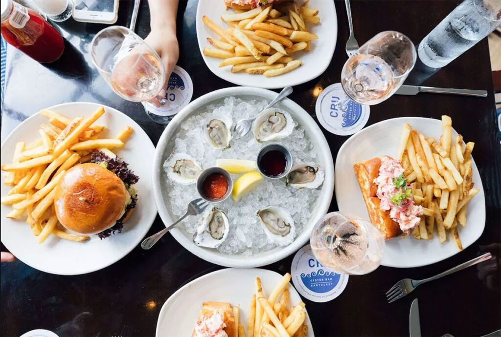 overhead shot of CRU oysters, lobster rolls, fries, and a burger